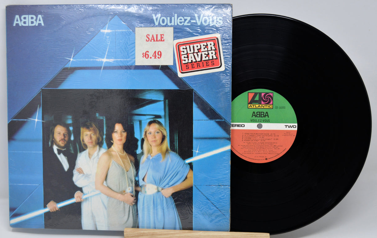 Vinyl record with cover featuring a band and sale tag on a light gray background