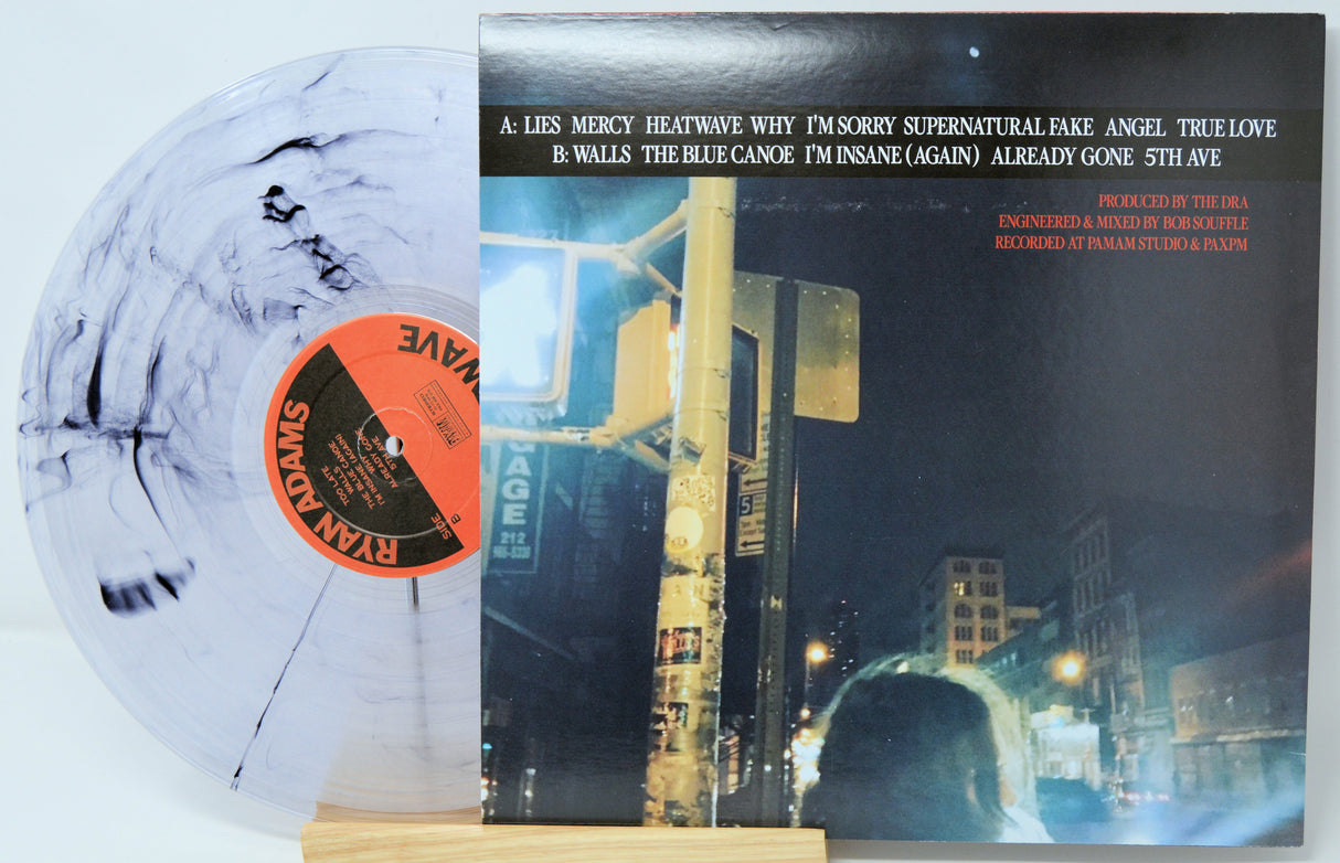 Vinyl record with a cityscape cover and a white disc with black patterns.