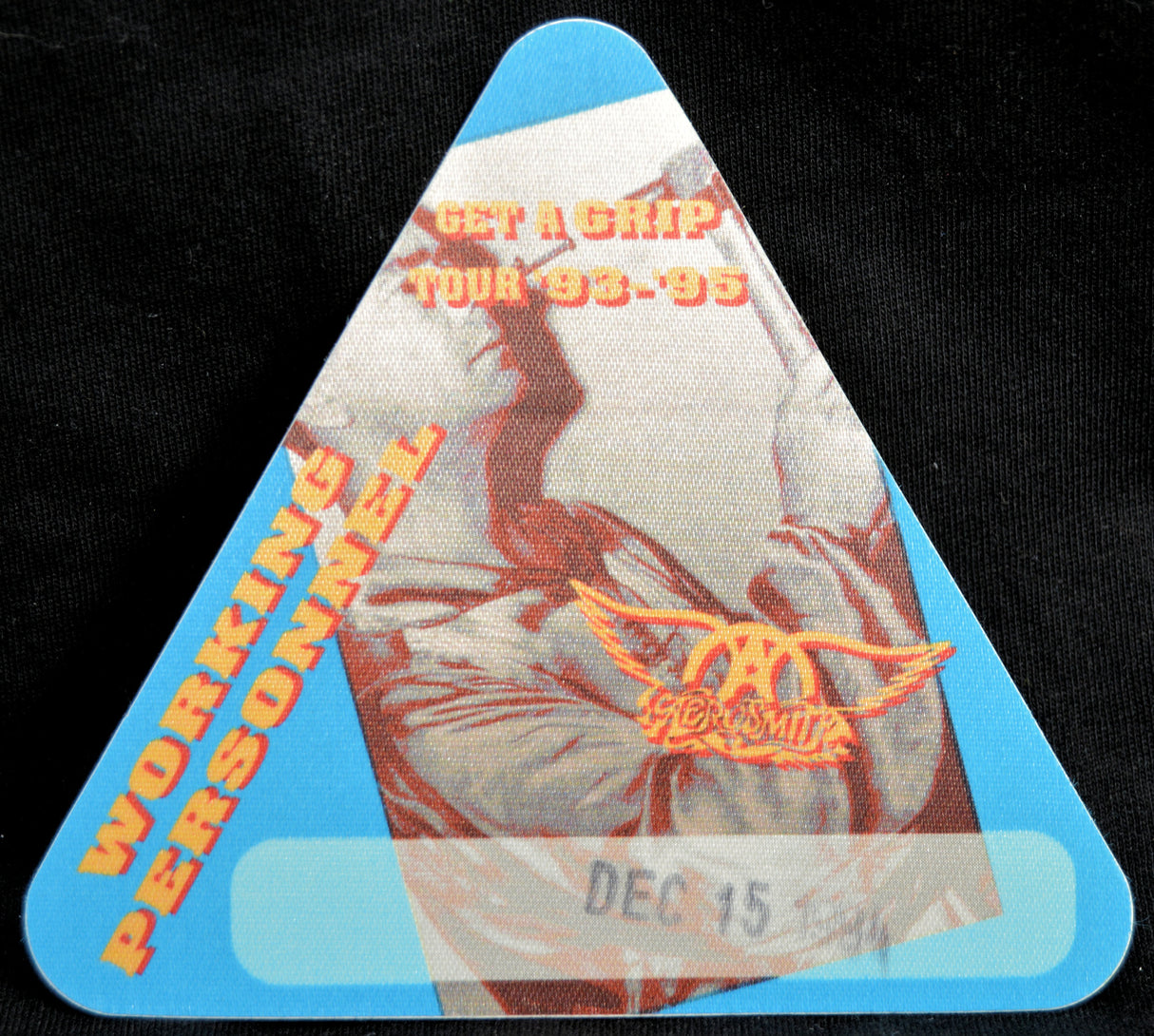 Triangular Aerosmith backstage pass with logo and text on a blue background.