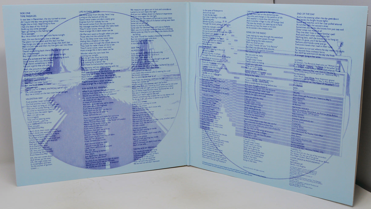 An open book or booklet spread open on a white surface, showing printed blue circular diagrams and text on pale blue pages.