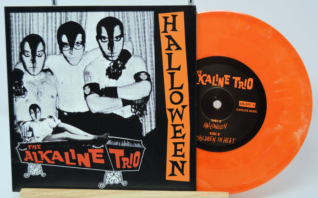 Orange vinyl record with black label featuring 'The Alkaline Trio' and black and white album cover on a white background