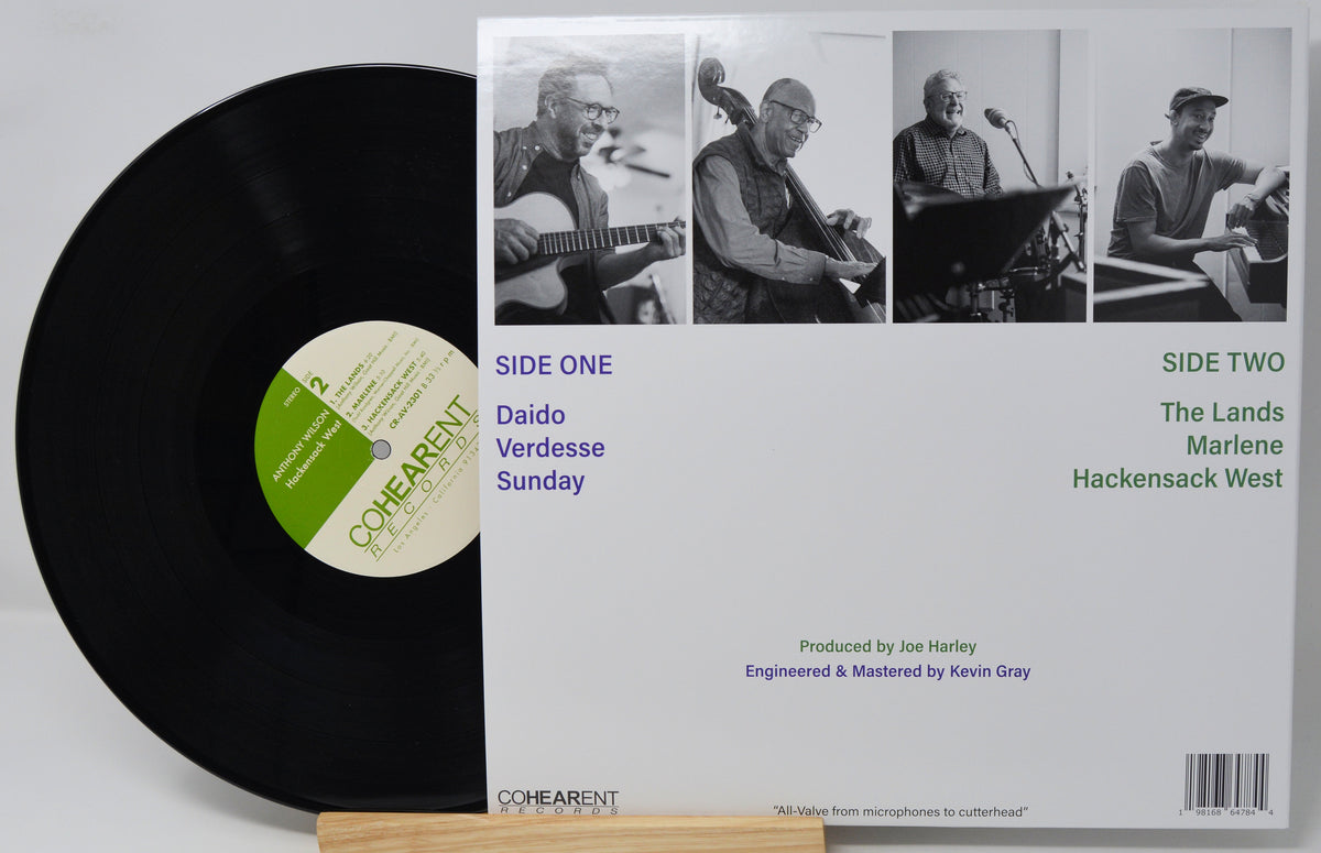 A vinyl record partially pulled from its album jacket, showing the black record and the white cover with black-and-white band photos and track listings for Come Arent's 'Side One' and 'Side Two'.