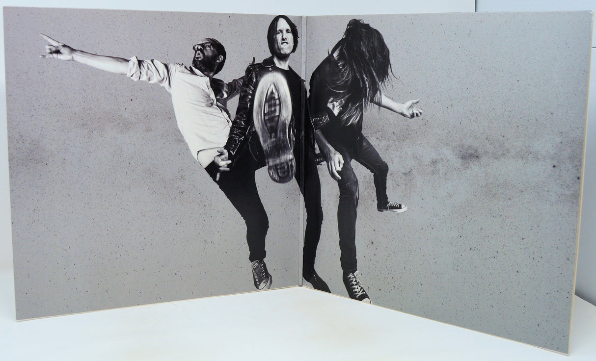 Black and white photo of three people in a dynamic pose on a textured gray background