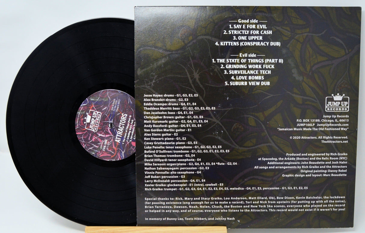 A vinyl record and its cover featuring a colorful abstract design with the artist and album name 'Attractors - Love Bombs'.
