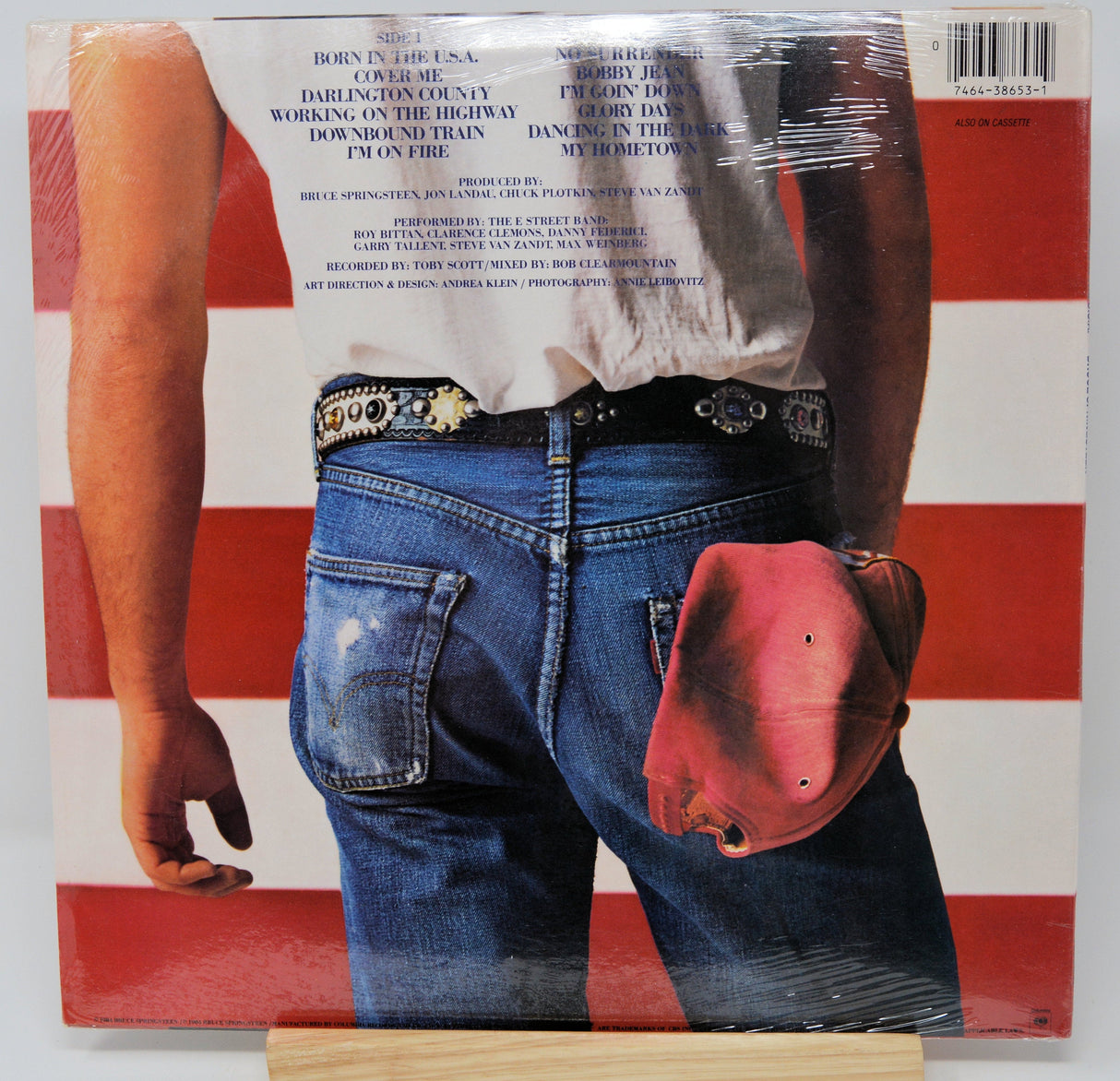 Back cover of 'Born in the U.S.A.' vinyl album showing denim jeans, a white shirt, and red cap against an American flag background