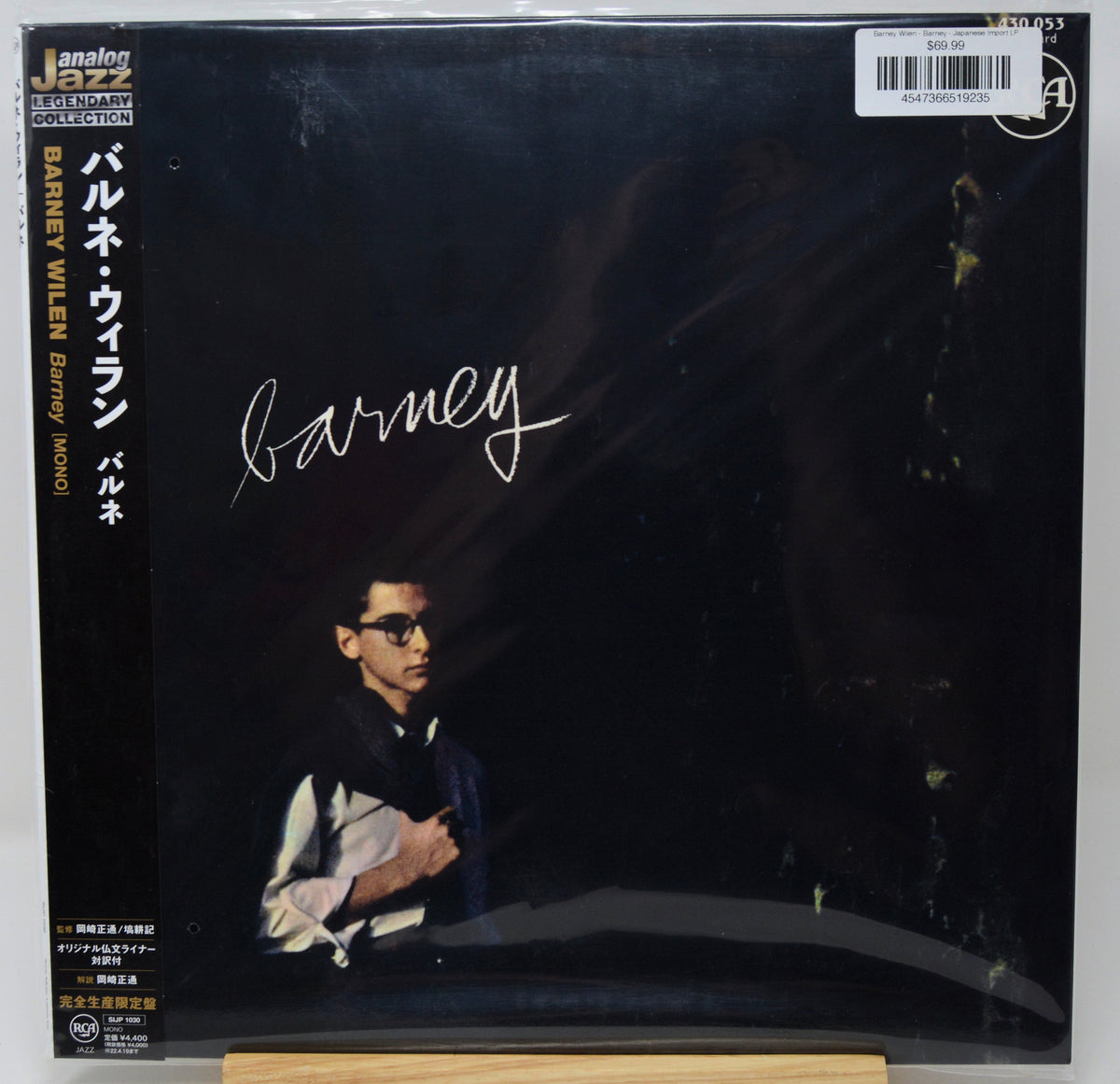 Barney Wilen's 'Barney' vinyl record album cover, released on Analog 55. The black cover features a photo of the artist in sunglasses, a white script signature, and Japanese text, and is shown sealed in its plastic shrink wrap on a wooden display stand.
