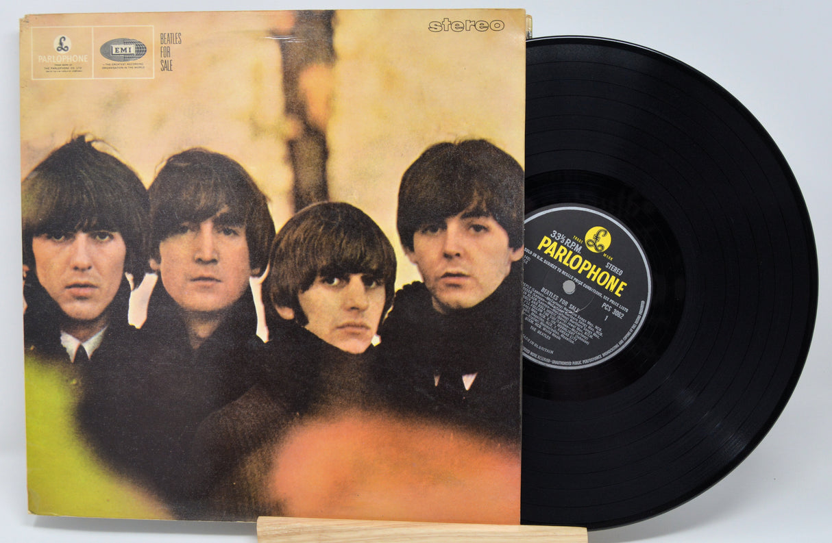 The image shows a vinyl record of The Beatles album 'For Sale' with the band members' faces on the cover.