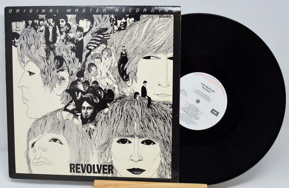 Vinyl record with cover featuring artistic design of faces and text 'Revolver'.