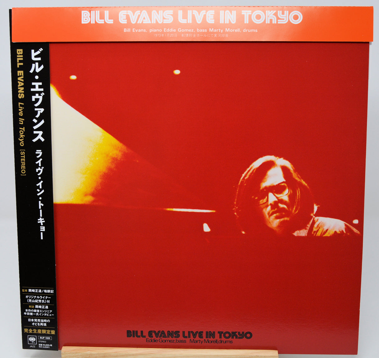 Bill Evans 'Live in Tokyo' album cover, Japanese edition, LP with obi strip, photographed standing upright on a small wooden display block against a light gray background.