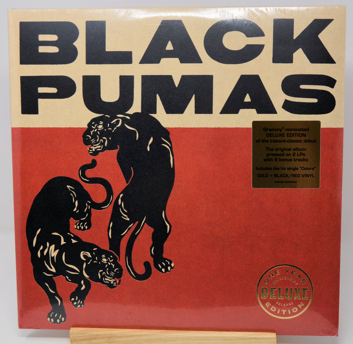Black Pumas 'Greatest Hits Deluxe Edition' vinyl record album cover, featuring two black panthers on a red background with a beige header and black text. A gold sticker on the right details the 2 LP set, and a round '40th Year Deluxe Edition' seal is visible at the bottom right.