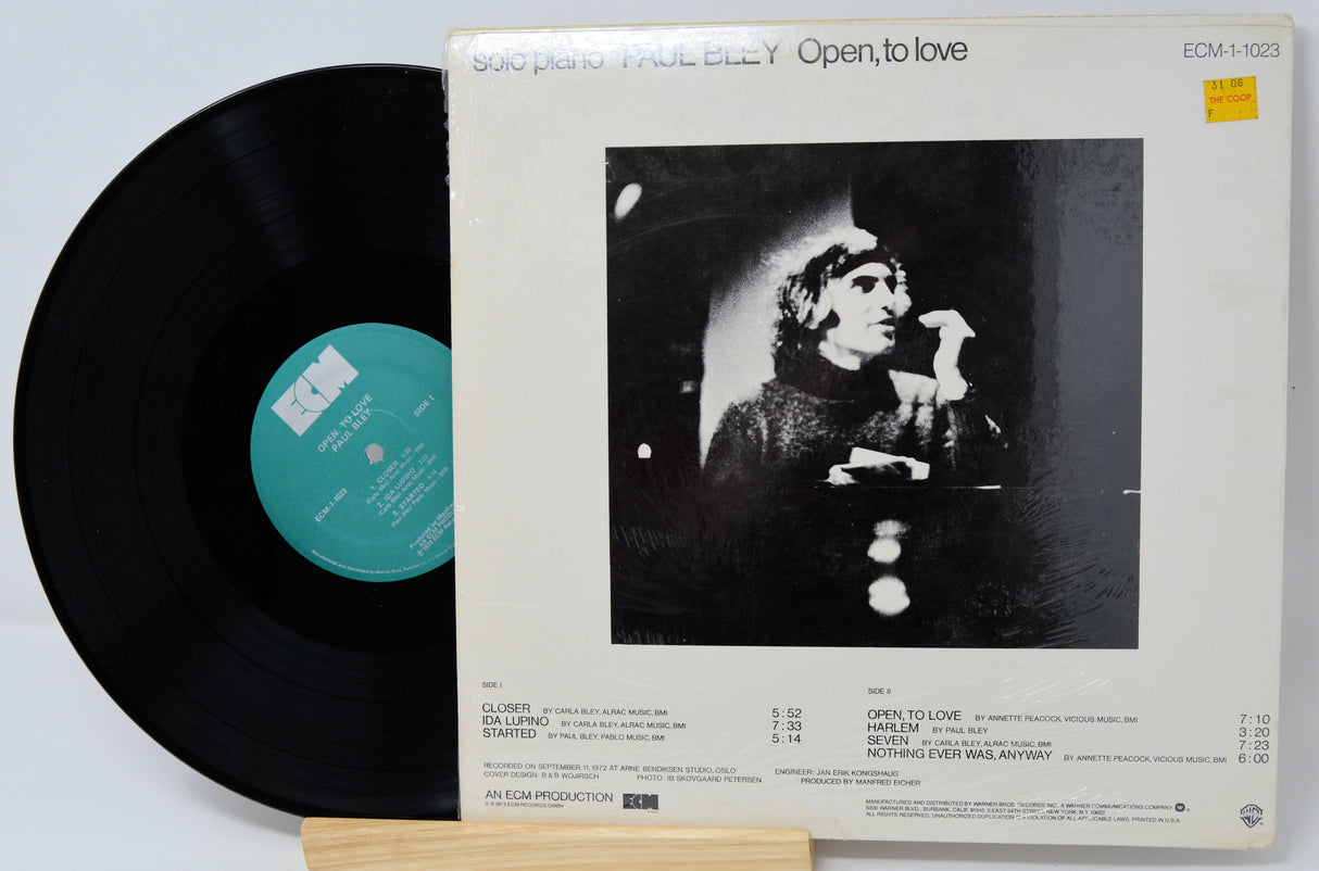 Vinyl record and its cover with a black and white image of a person on a light gray background