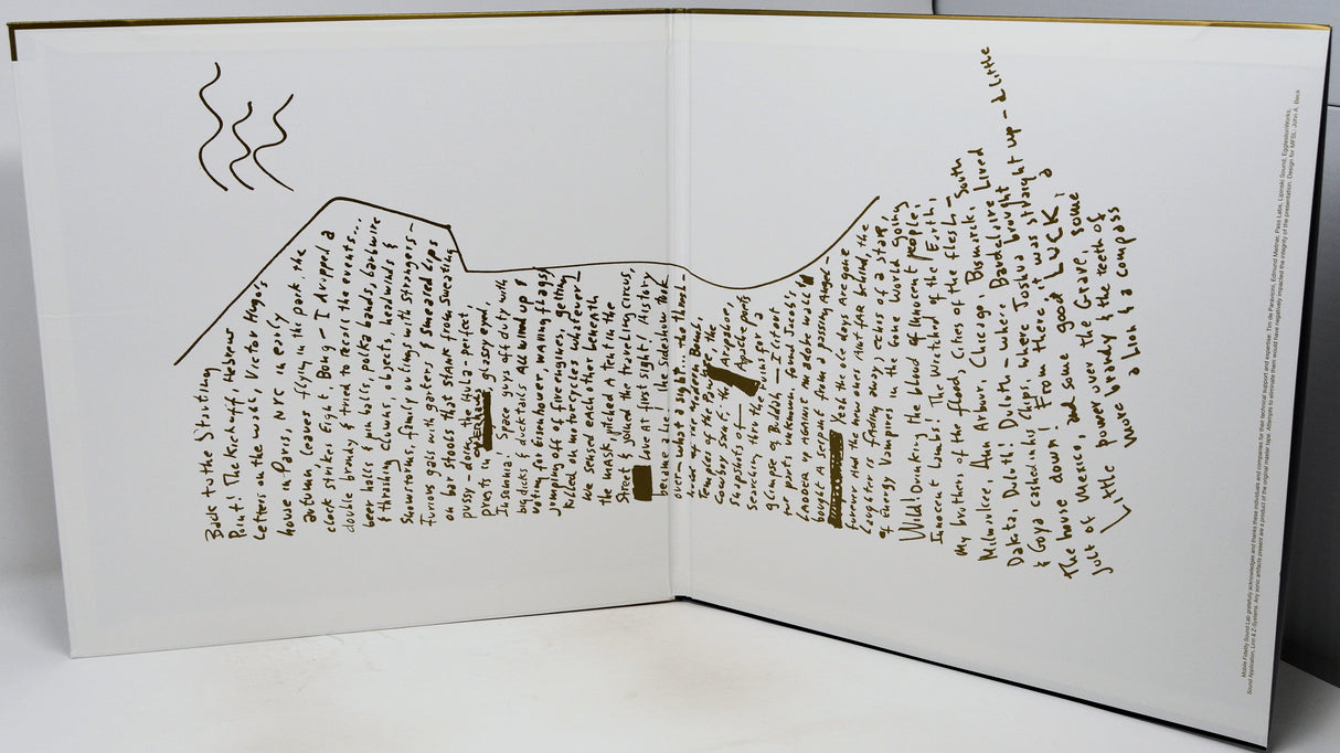 An open book or printed booklet on a white surface, showing a detailed topographic-style map drawn in brown ink with handwritten text throughout the pages.