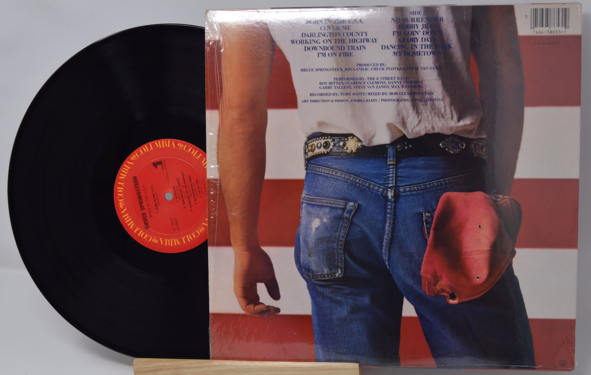 Vinyl record with a red label and cover featuring a person in blue jeans and a red hat.