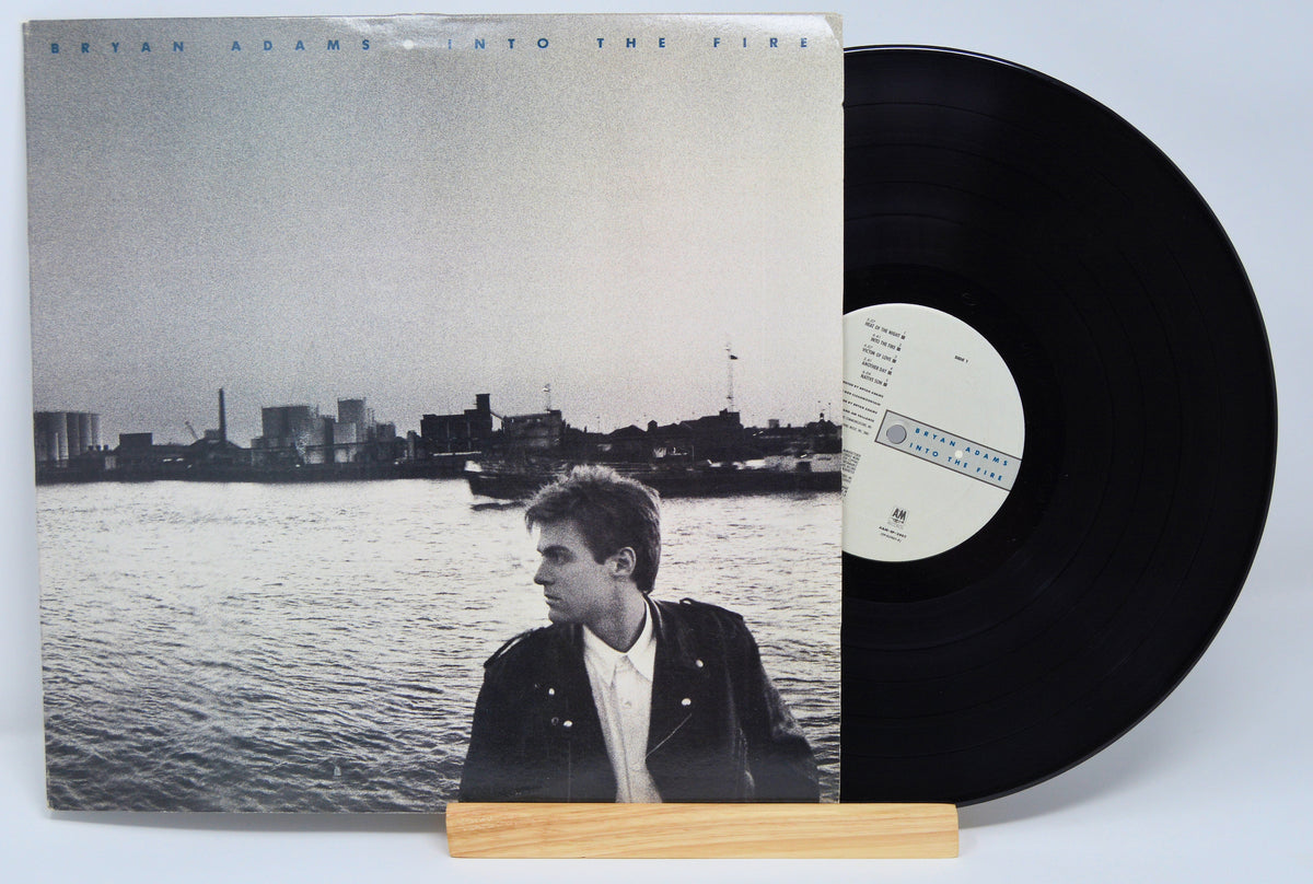 Vinyl record with a cover featuring a person by a waterfront, on a light gray background.