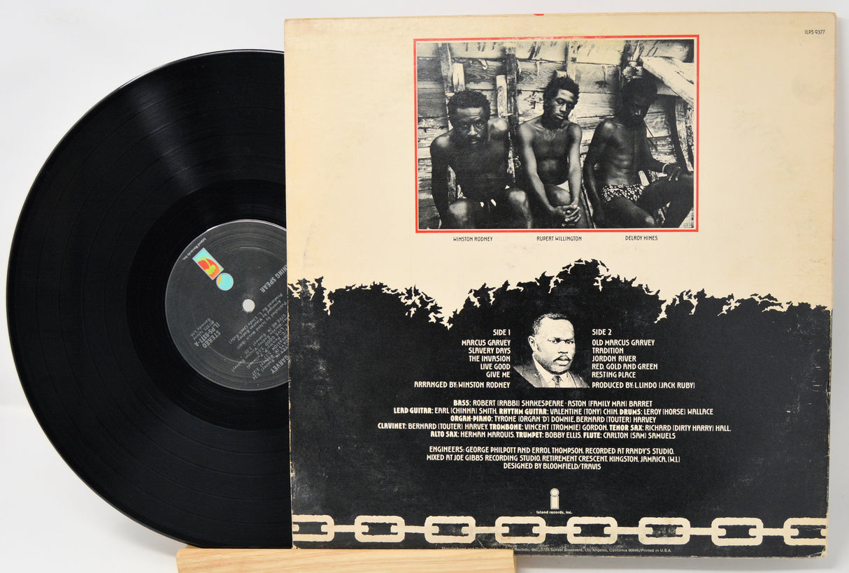 Vinyl record with its cover featuring a black and white photo of three people and text.