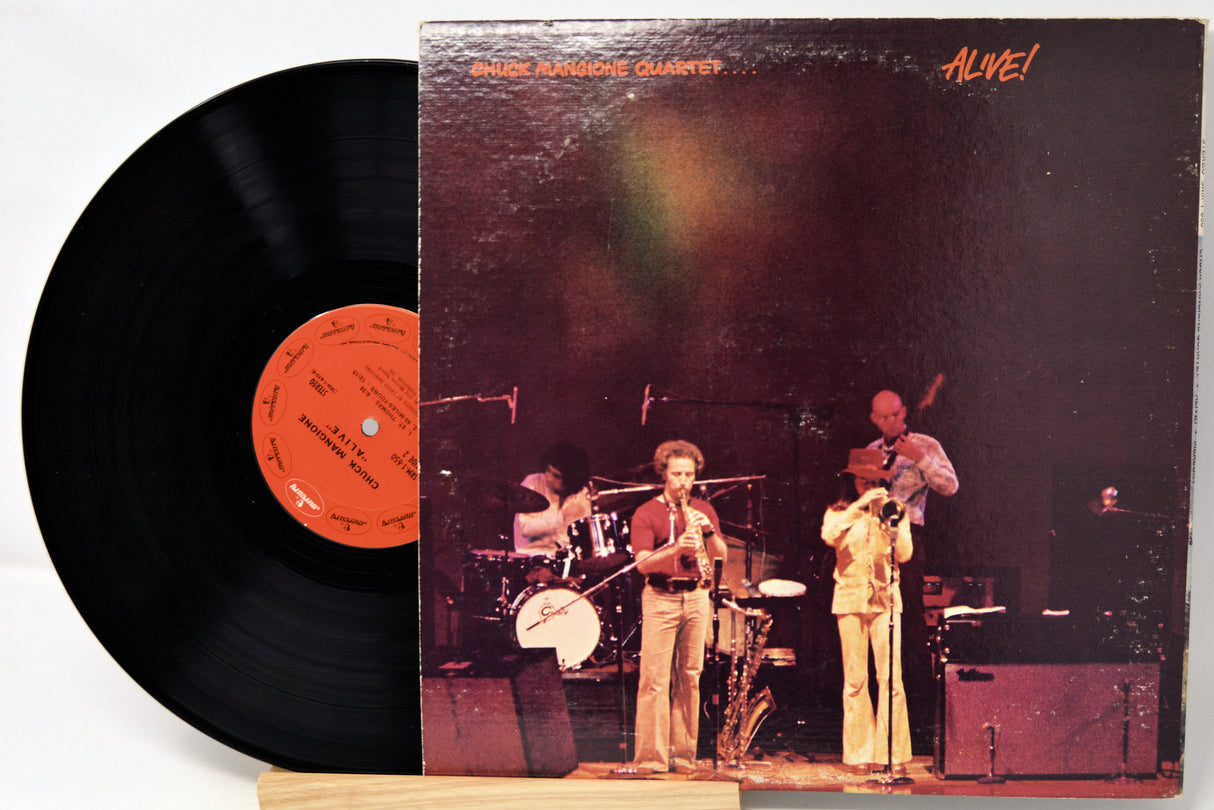 Vinyl record with a cover featuring a band on stage and 'Alive!' text.