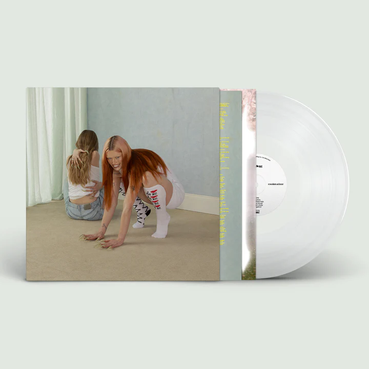 Limited edition clear vinyl record with bold artistic album cover featuring two individuals, one crouching with vivid red hair.