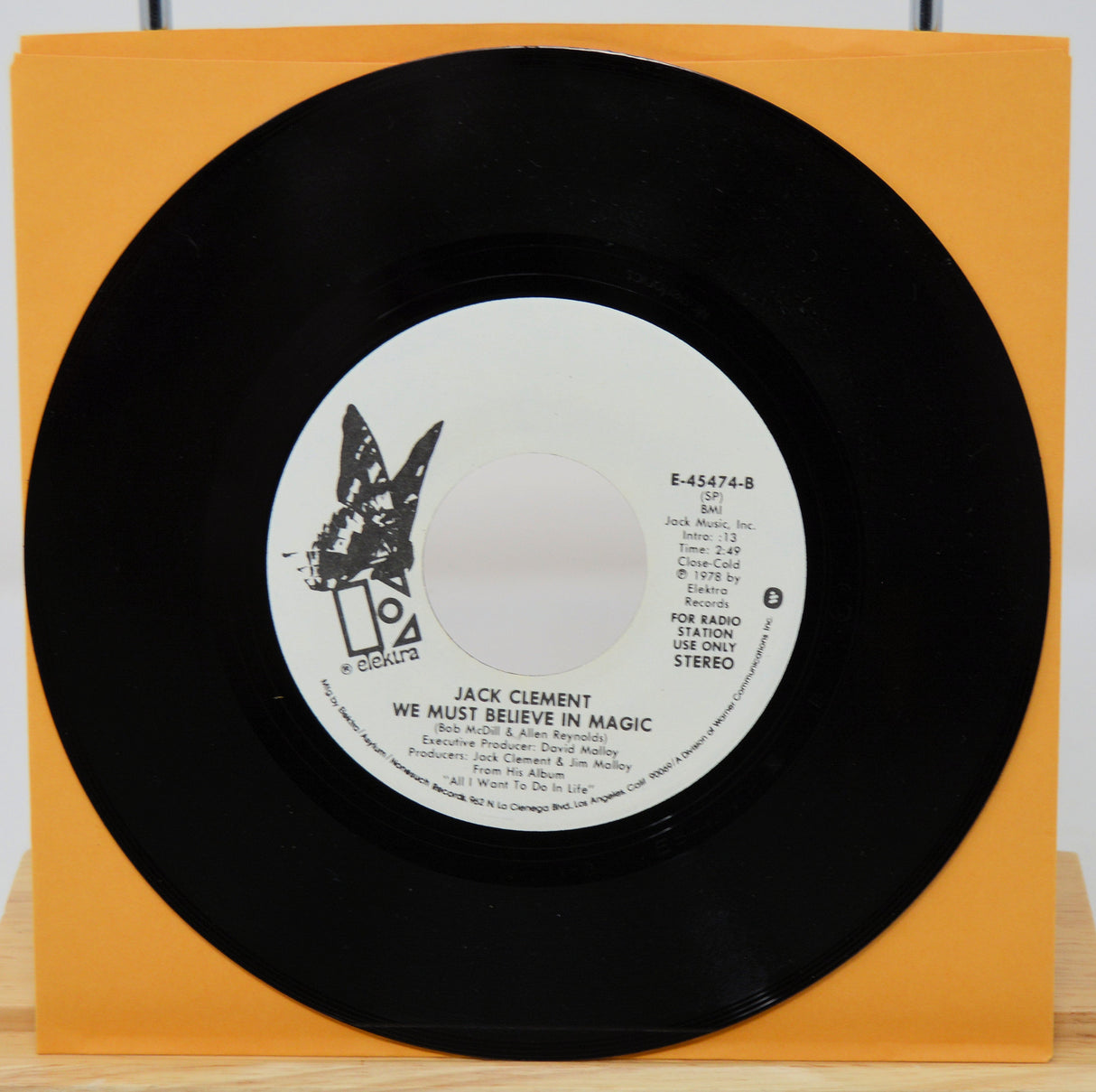 Black vinyl record with a butterfly design on an orange sleeve against a white background
