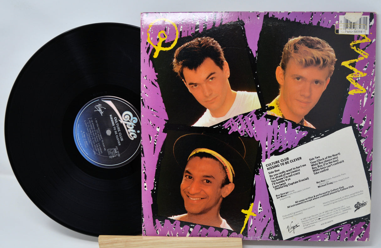 Vinyl record with a colorful cover featuring three men's faces on a purple background.