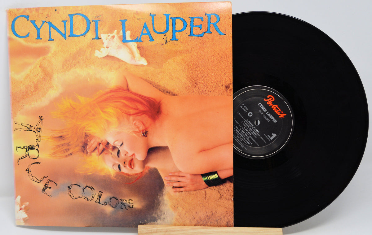 Cyndi Lauper album 'True Colors' with a portrait of the artist on the cover, placed on a wooden surface.