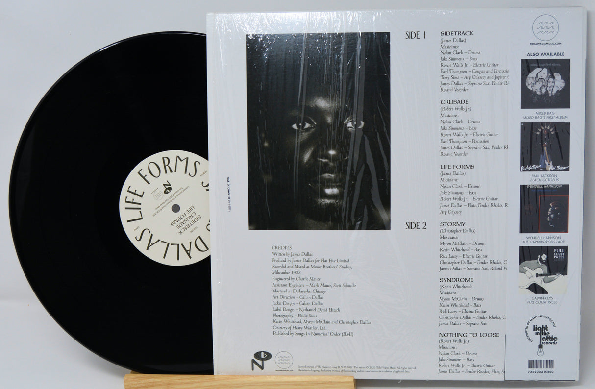 Vinyl record with cover displaying tracklist and album art on a light gray background