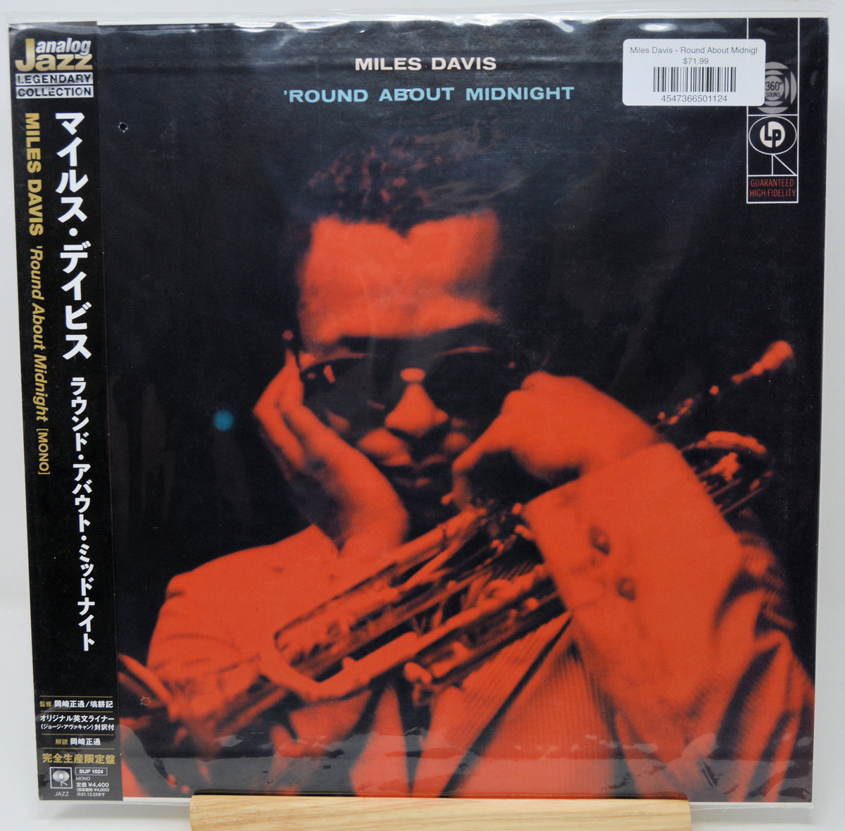 Miles Davis 'Round About Midnight' vinyl record cover, Japanese edition, with a red-tinted photo of the artist playing trumpet and Japanese text on the left side. The record is sealed in plastic shrink wrap.