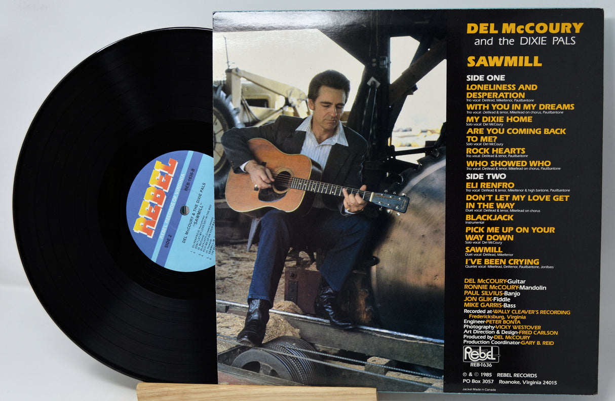 Del McCoury and the Dixie Pals 'Sawmill' vinyl record with the black LP partially visible behind the album cover, photographed on a light neutral background.