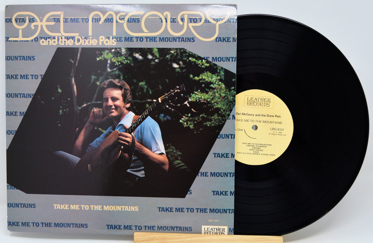 Del McCoury and the Dixie Pals 'Take Me to the Mountains' vinyl record album with the LP partially pulled from the jacket, showing the black record, cream label, and printed cover art.