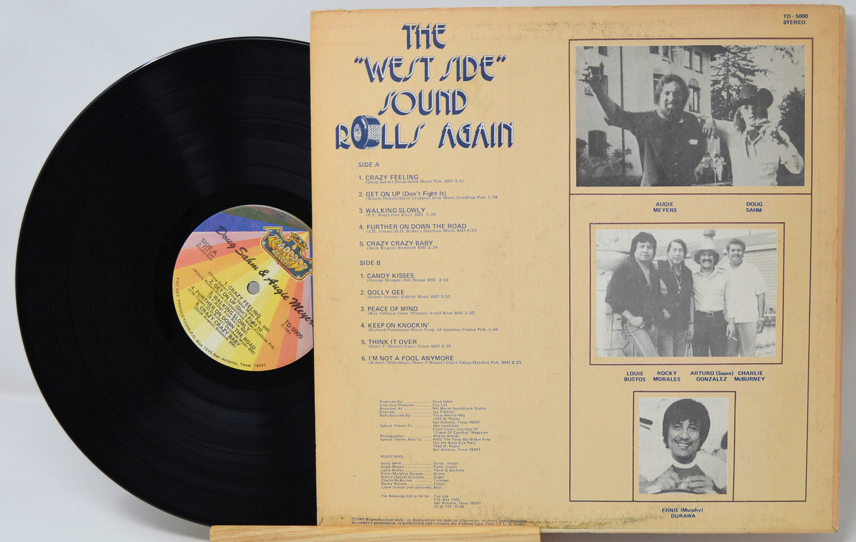 Vinyl record album shown with the black record partially visible behind the printed inner sleeve. The sleeve has blue title text reading "The 'West Side' Sound Riffs Again" and several black-and-white photos on a tan background.