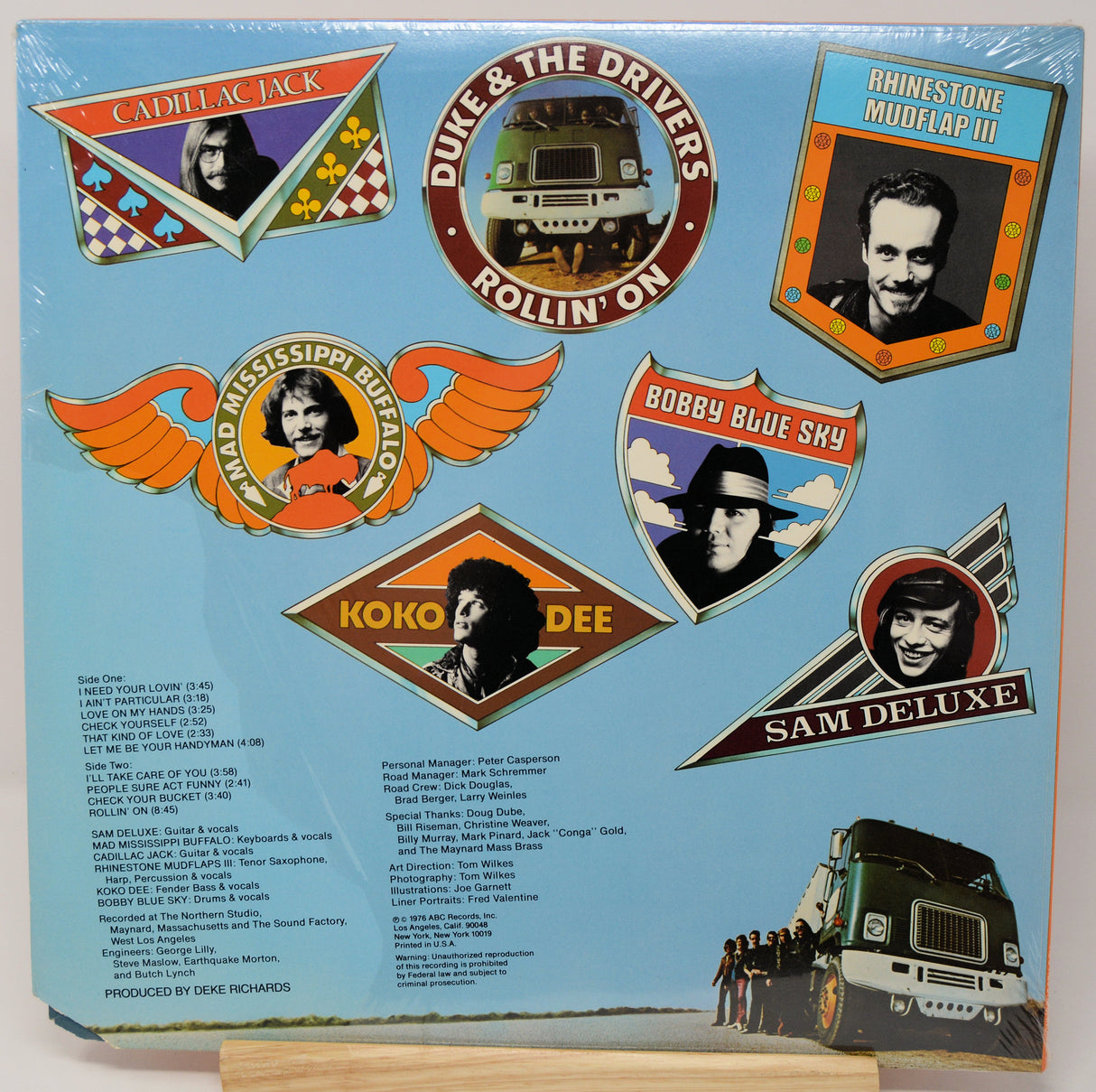 Album cover with various music labels and a truck illustration on a blue background