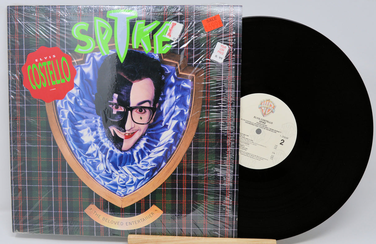 Vinyl record with cover featuring a stylized portrait and text, on a light gray background.