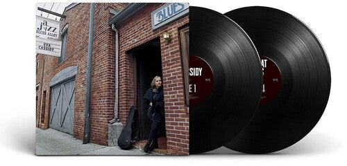 Two vinyl records with a person standing in front of a brick building with a 'Blue' sign.