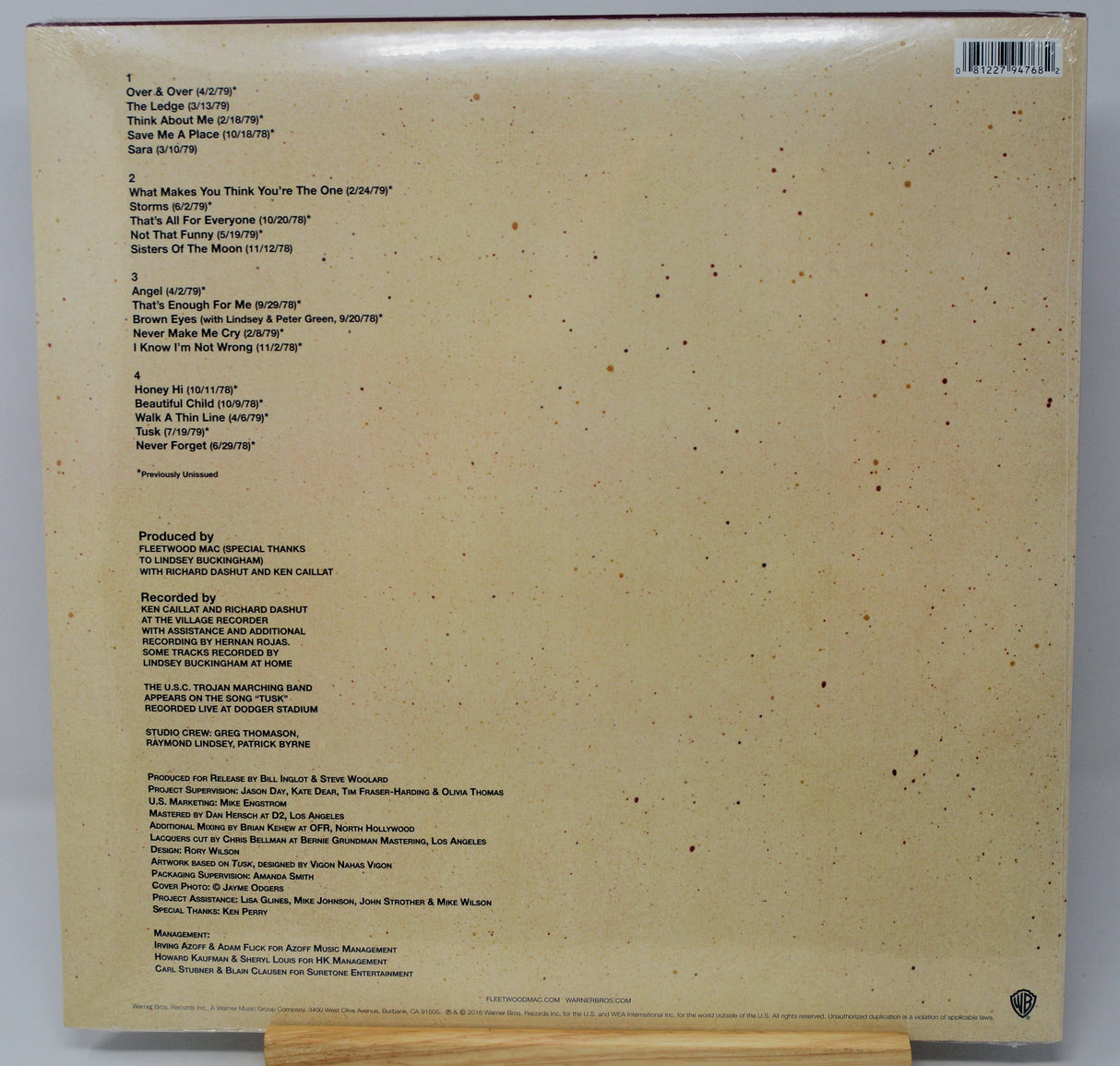 The back cover of a vinyl record sleeve, showing the tracklist, production credits, and barcode on a beige background with small dark speckles.