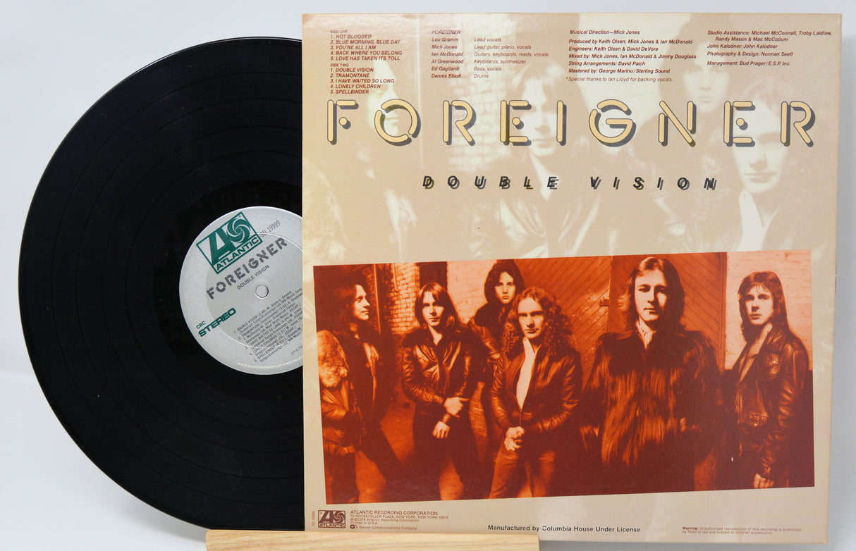 A used vinyl record of Foreigner's album 'Double Vision' with the band members pictured on the back cover with text for the song titles.