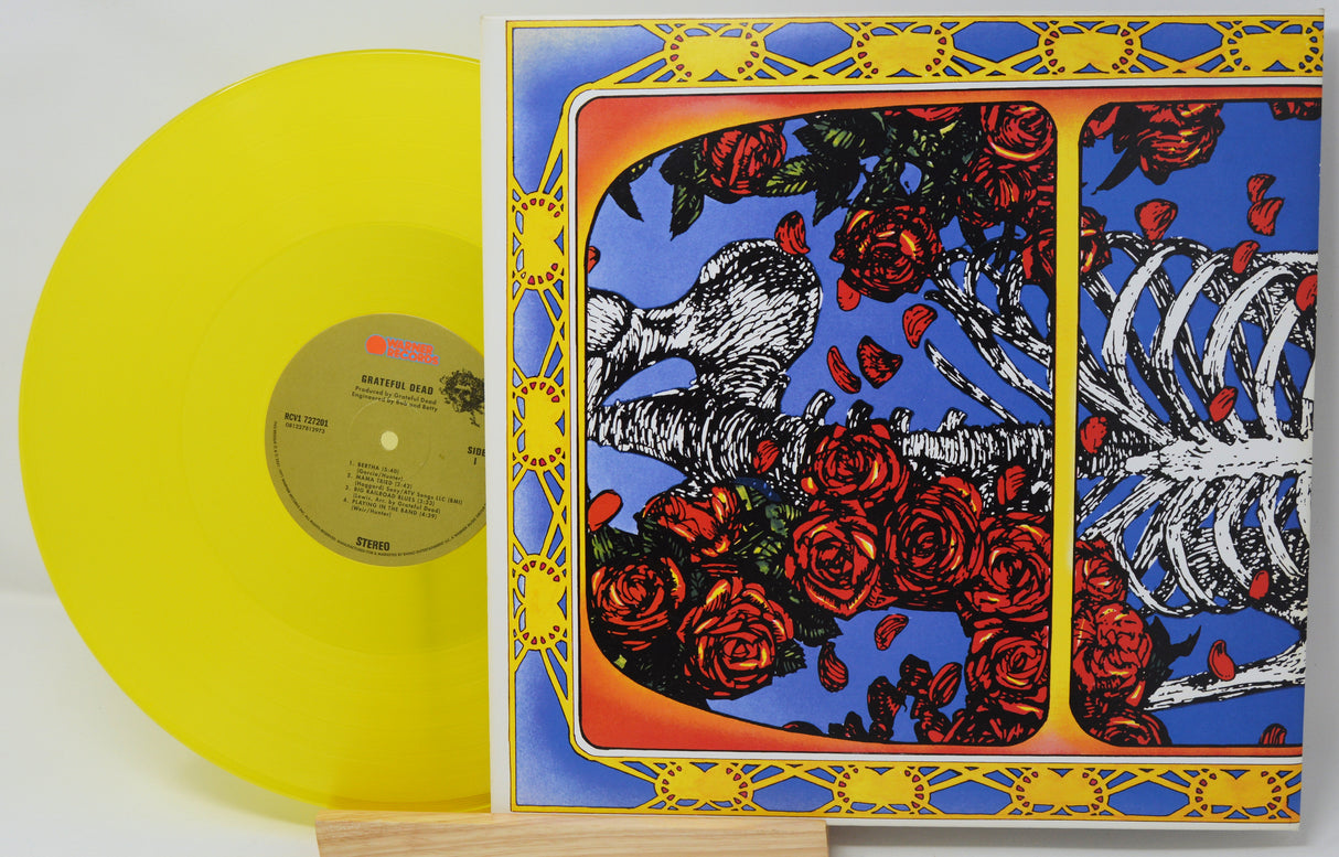 Vinyl record with a colorful cover featuring roses and a skeleton, on a white background.