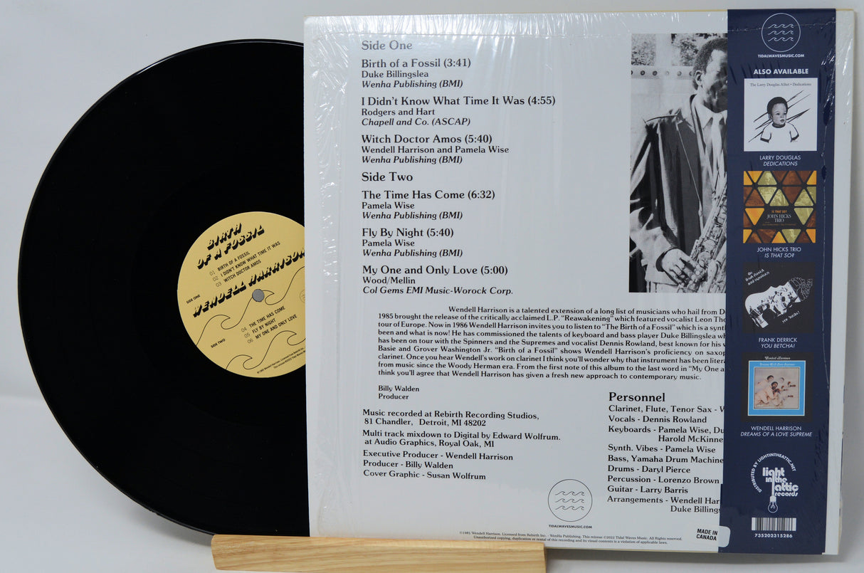 Vinyl record with black disc and white label on a stand, showing text and a small yellow label.