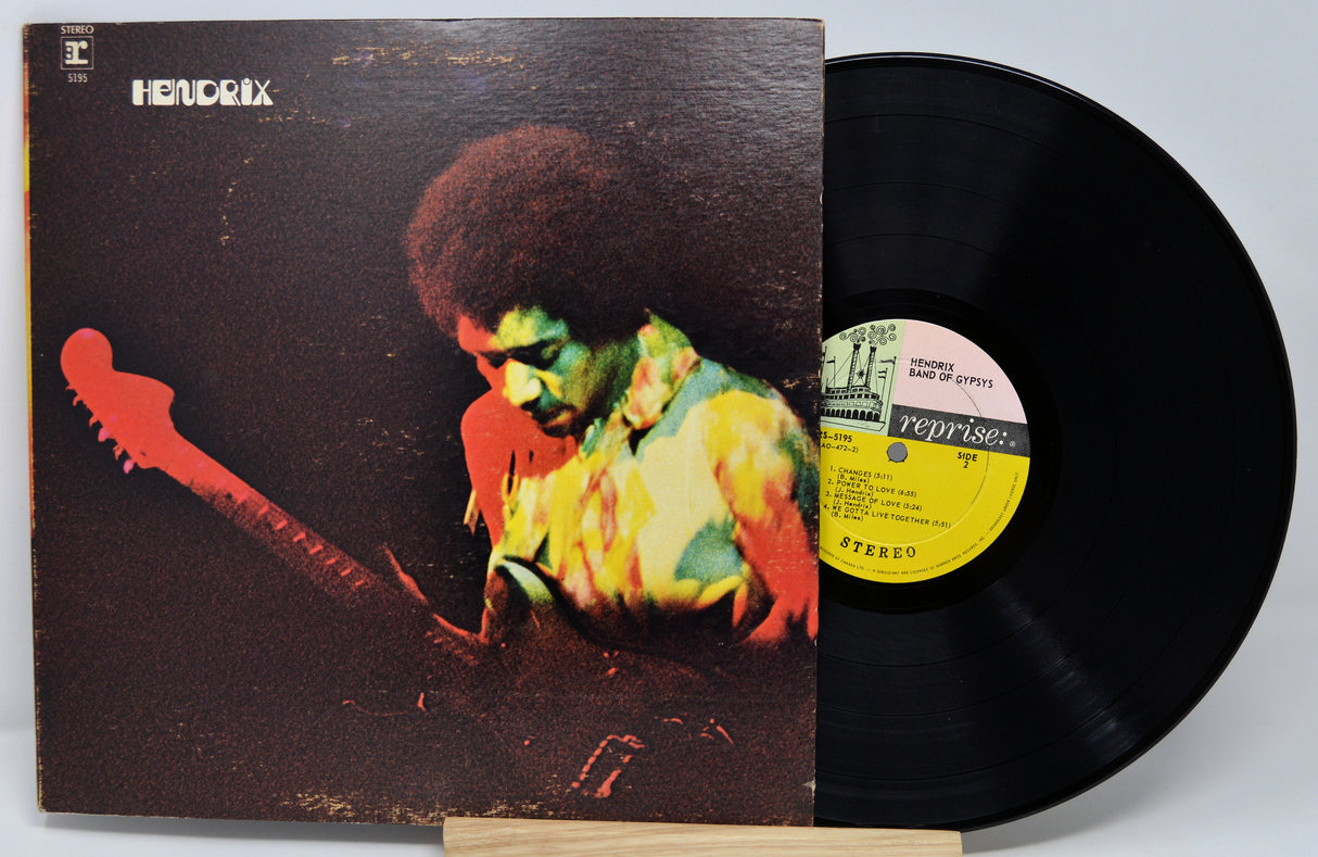 Vinyl record with a colorful cover featuring a person playing guitar, on a white background.