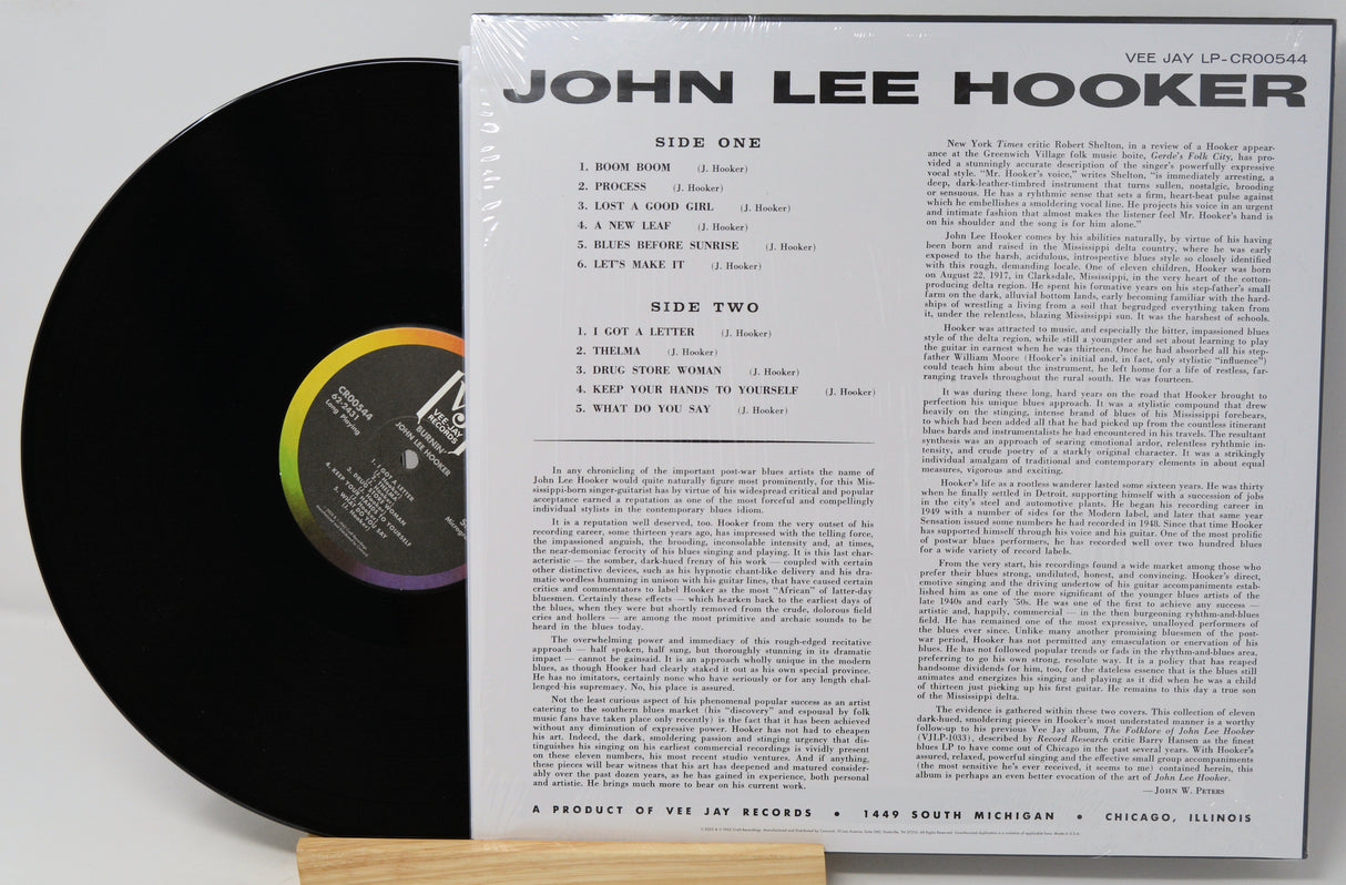 A vinyl record partially pulled from its sleeve, showing the black record on the left and the printed inner sleeve track listing on the right. The sleeve reads 'JOHN LEE HOOKER' and 'VIE JAY LP-CRS0054'.