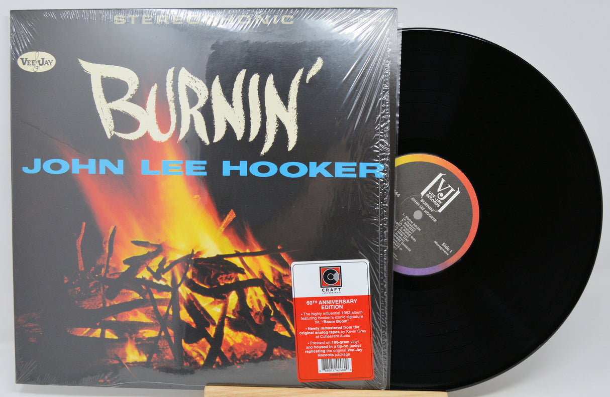 Vinyl record album 'Burnin'' by John Lee Hooker, shown with the black LP partially pulled from the sleeve. The sleeve features a fiery graphic and the artist's name in blue text.