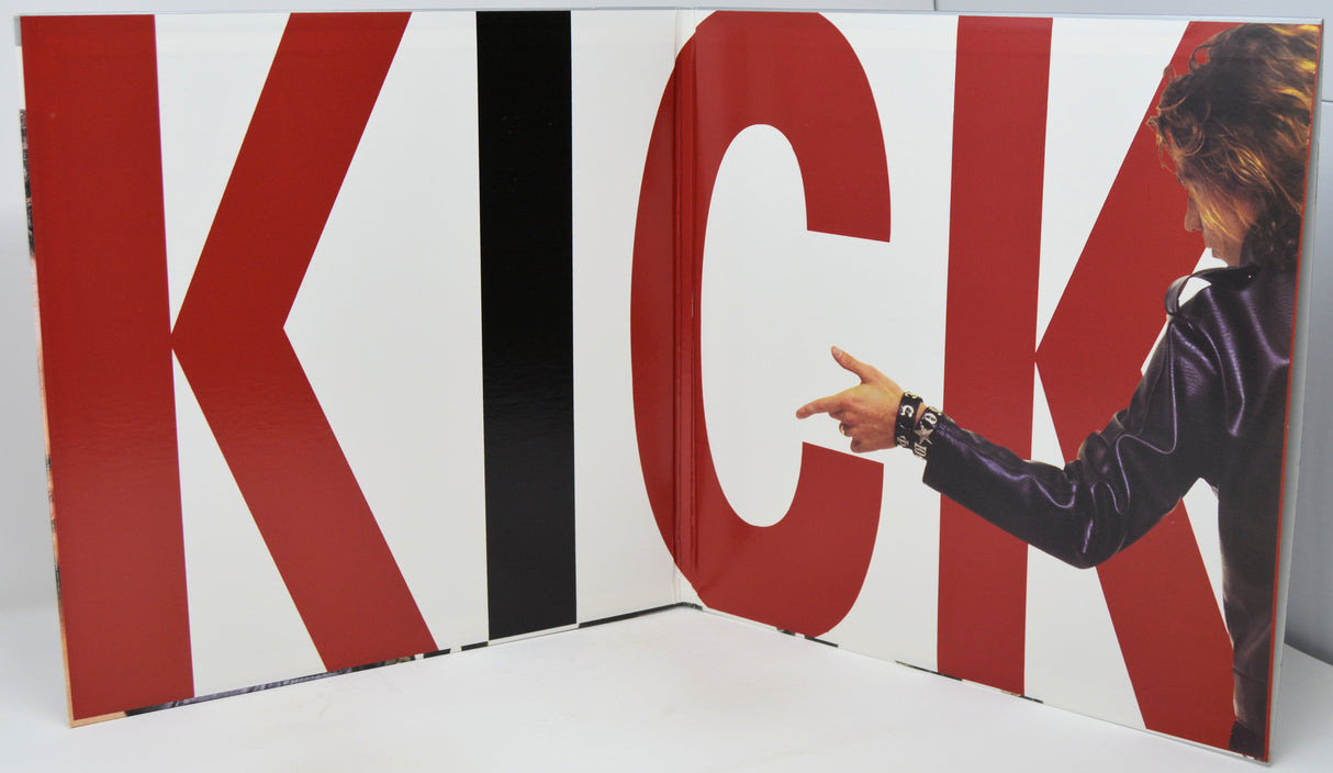 A large printed panel or book-like display featuring oversized red, white, and black letters spelling KICK, with a partial photo of a person in a dark jacket pointing toward the letter K. The product appears to be the printed panel itself rather than a lifestyle scene, so this is classified as Product/Packaging.