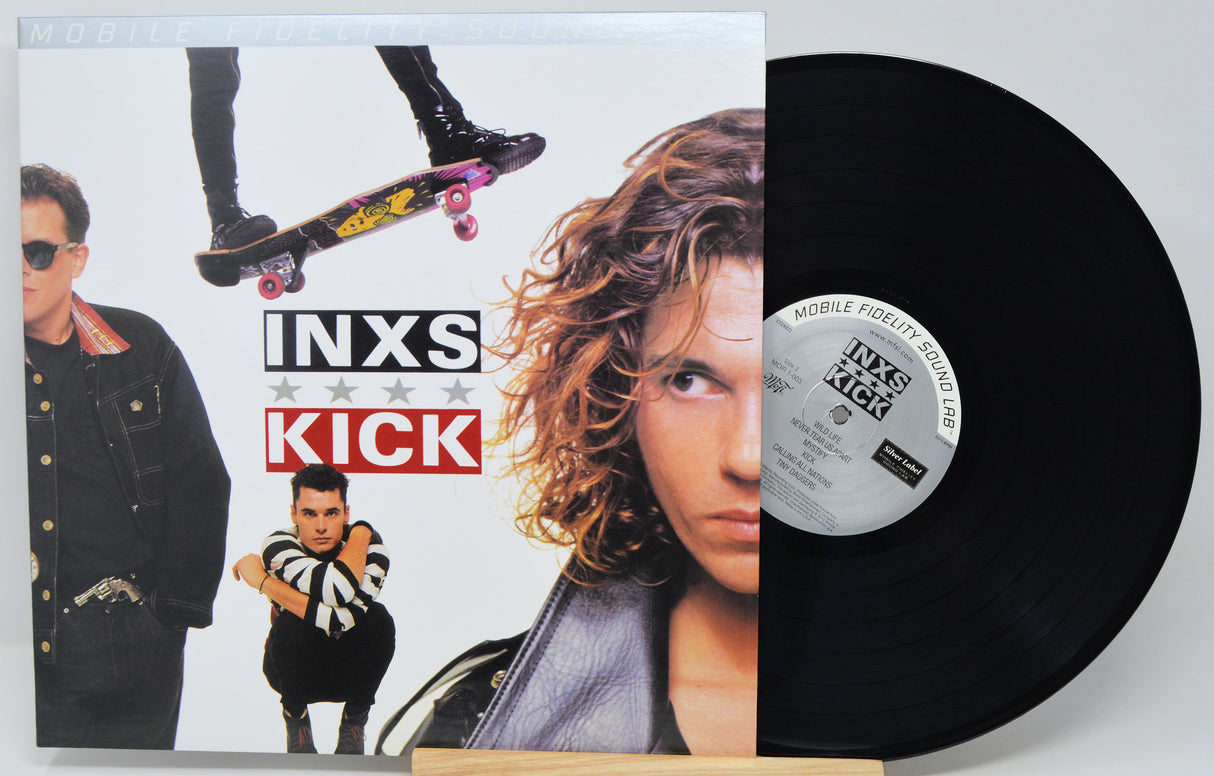Inxs - Kick vinyl record LP with its illustrated cover sleeve and the black vinyl record partially pulled out, displayed on a light gray background.