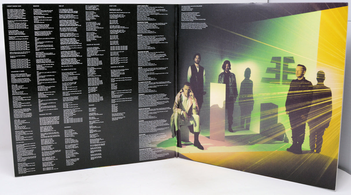 Vinyl record with a black cover featuring text on the left and a colorful album cover on the right with people in a room.