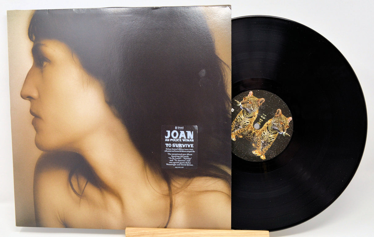 Front cover and vinyl record of Joan As Police Woman's 'To Survive' album featuring a woman's profile