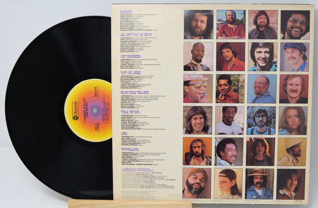 Vinyl record with a colorful label and a cover featuring portraits on a light gray background