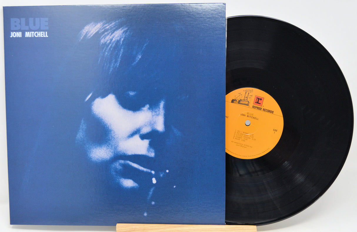 Jon Mitchell's album 'Blue' vinyl record, showing the blue cover with a high-contrast face print and the black LP disc partially pulled out, revealing a yellow label.