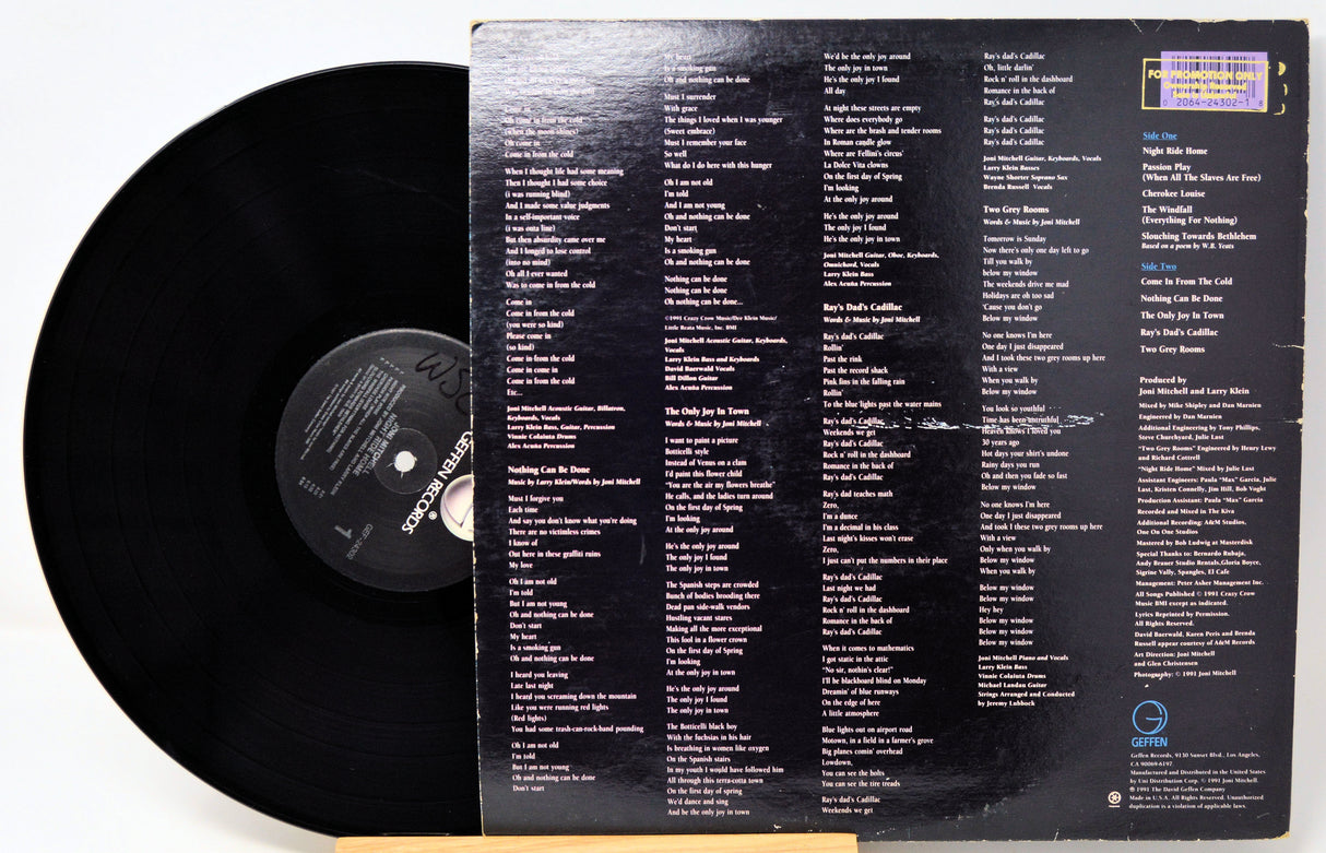A black vinyl record partially pulled from its back cover sleeve, showing printed track listings and text on both the record and sleeve against a plain light background.