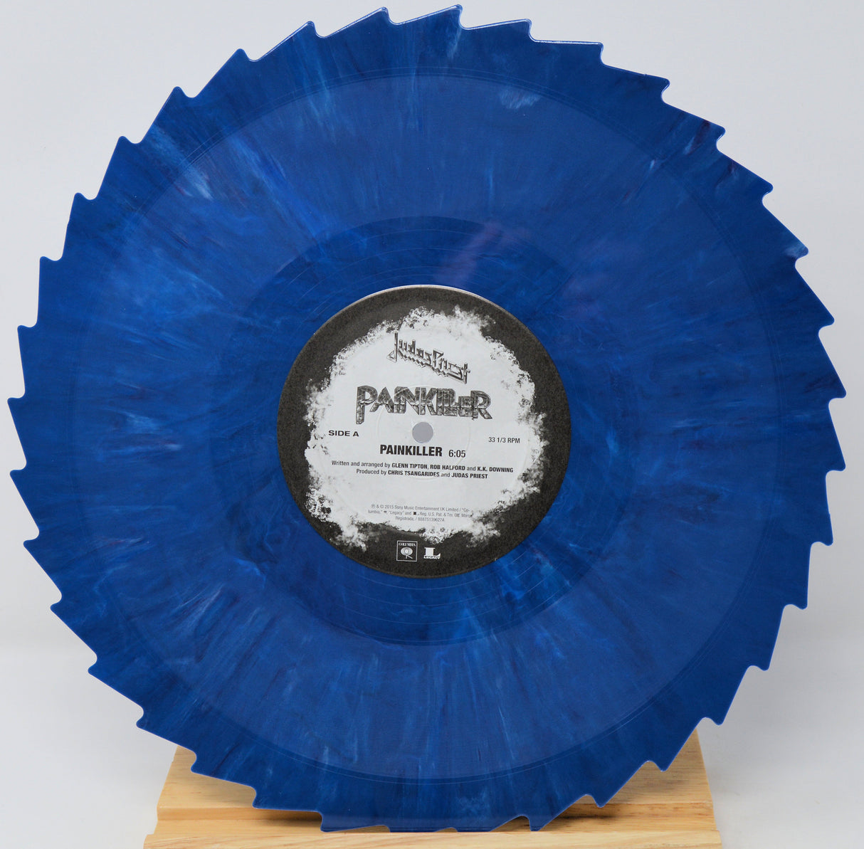 A blue marbled vinyl record with a jagged outer edge, displayed on a small wooden stand against a light gray background. The center label reads 'PANKER' and 'PAINKELLER'.