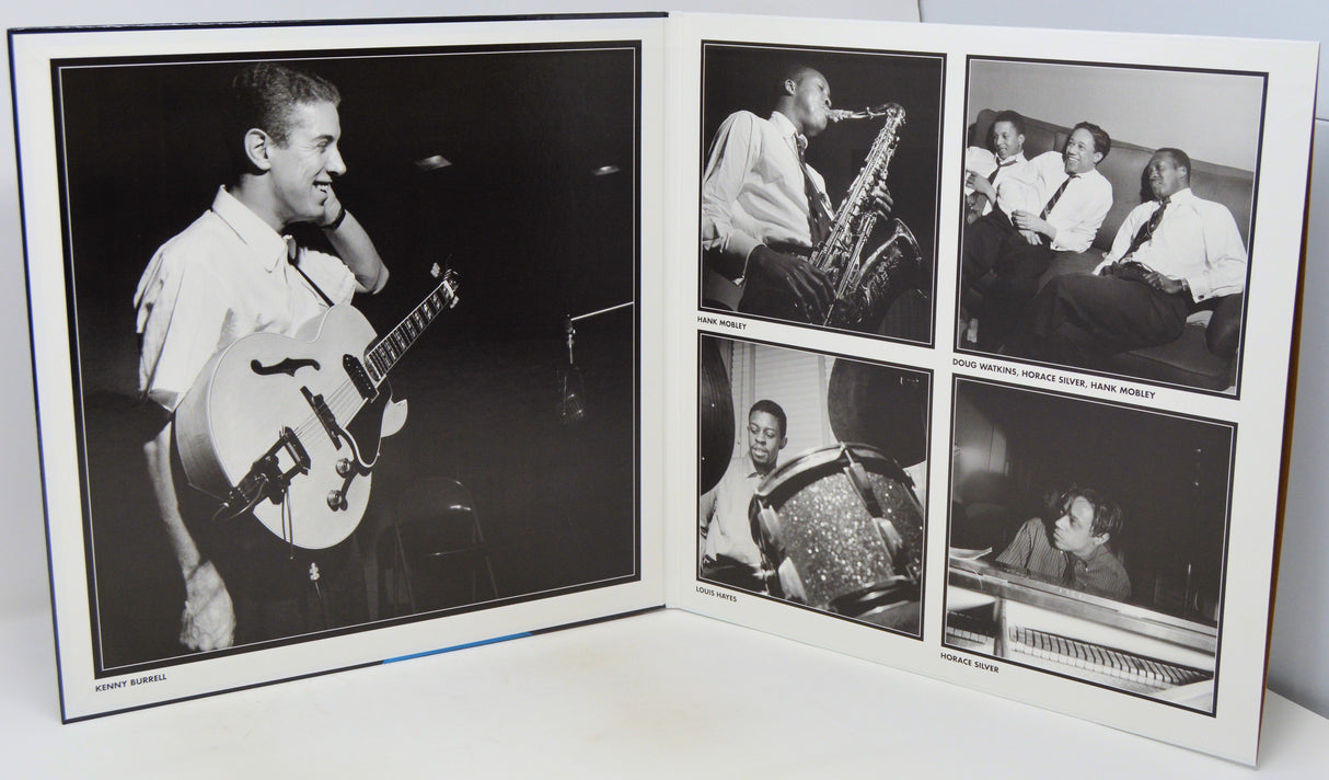 An open printed album or photo book showing black-and-white photographs of a musician performing, photographed on a white surface against a white background.