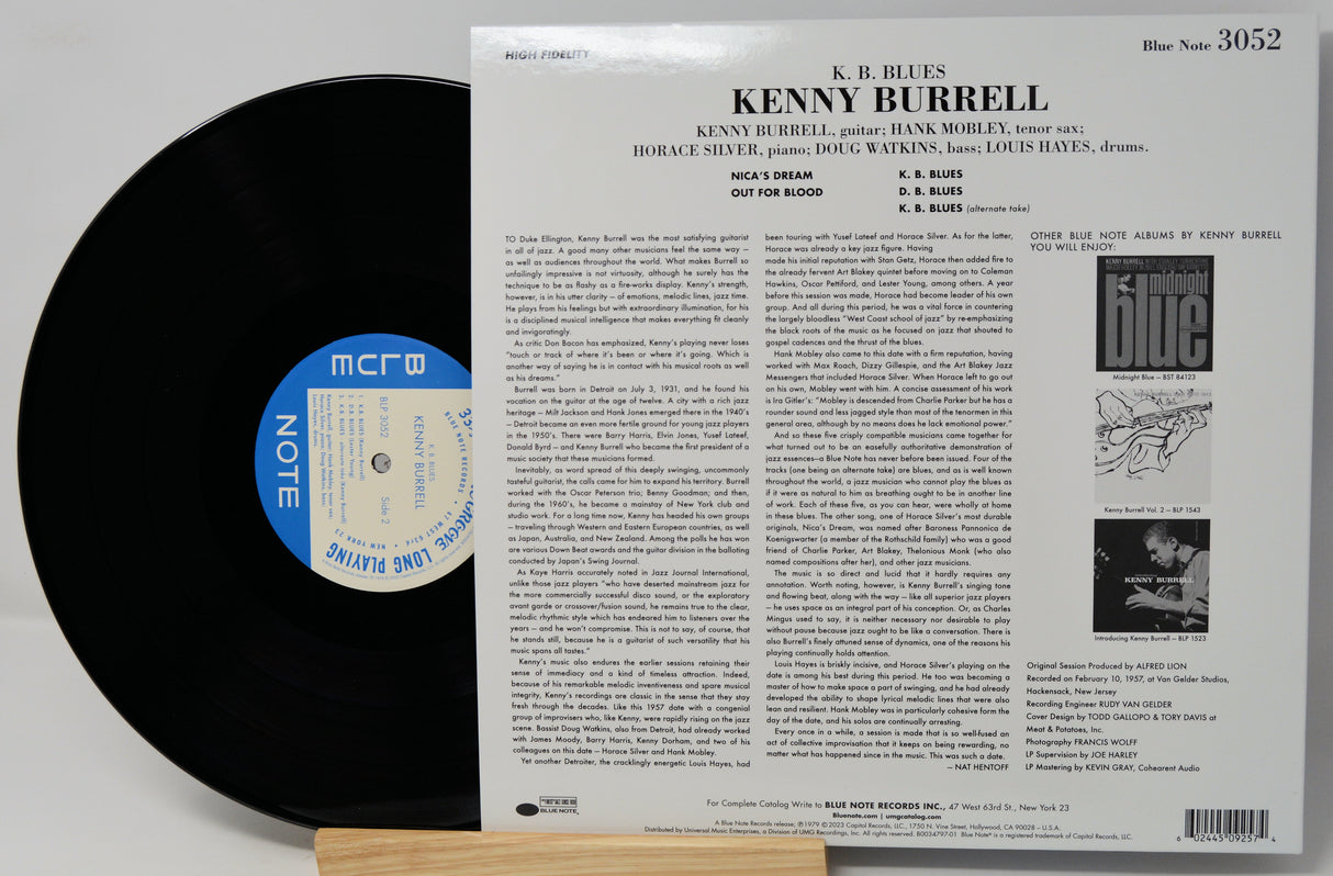 Vinyl record album shown with the black LP partially visible behind the back cover insert. The back cover reads Kenny Burrell and lists track titles and credits, with a blue circular label on the record.