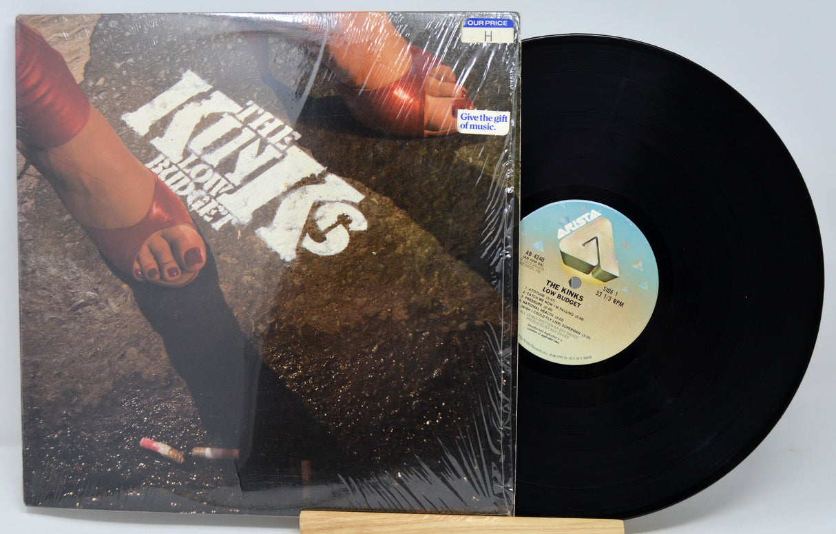 Vinyl record with cover featuring the feet of a woman in high heals smoking on a street, on a white background